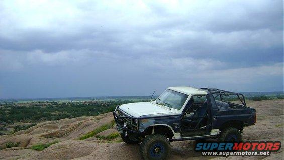 1986 Ford Bronco, two-tone off-road SUV with roll cage on rocky terrain