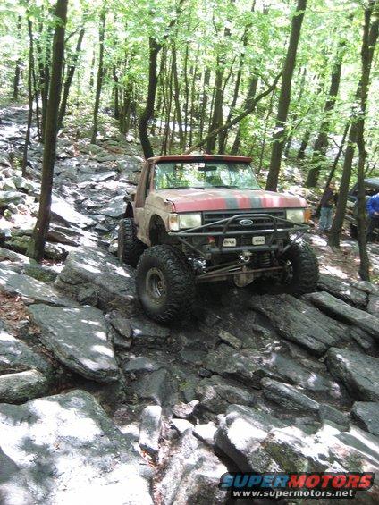 Red and grey 1991 Ford Bronco climbing a rocky trail