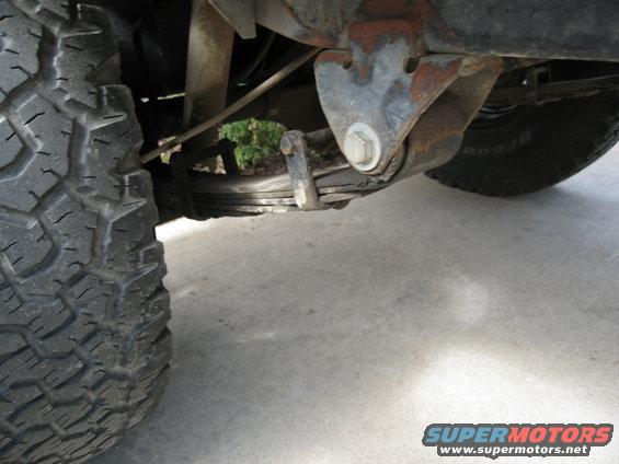Leaf spring suspension and tire on a vehicle, showing rust on the suspension bracket