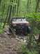 1991 Ford Bronco - A modified red Ford Bronco navigates a challenging rocky path through a dense forest.