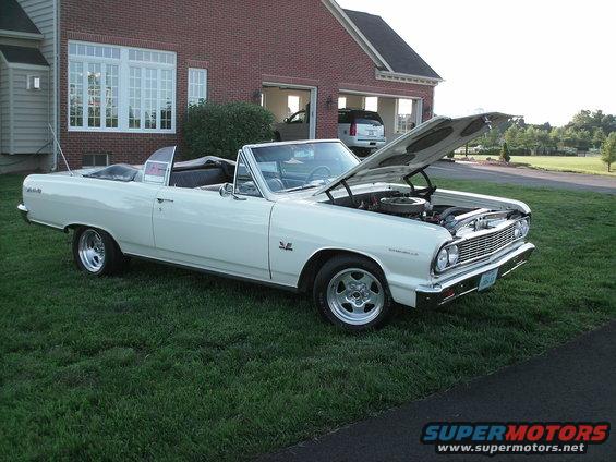 White 1964 Chevrolet Chevelle Malibu convertible with hood open, parked on grass in front of a brick house