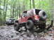 1991 Ford Bronco - Two off-road vehicles navigate a challenging rocky path through a dense forest.
