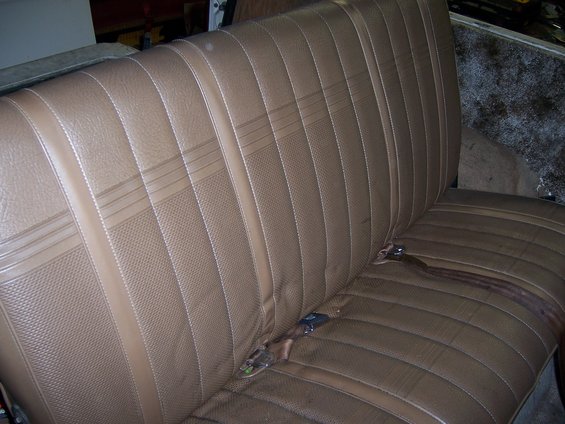 Brown vinyl bench seat with horizontal pleats and seatbelts