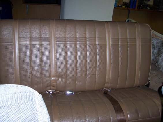 Brown vinyl bench seat with seatbelts and patterned upholstery