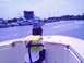 1979 Ford F-250 - A boy wearing a life jacket looks out from a boat at a marina with several other vessels docked.