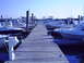 1979 Ford F-250 - A long wooden dock extends into a marina filled with various boats under a clear blue sky.