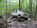 1991 Ford Bronco - This lifted Ford Bronco navigates a rocky path through a dense forest during an off-road event.