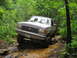 1991 Ford Bronco - 1991 Ford Bronco tackles a challenging off-road course through a wooded area.