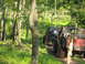 1991 Ford Bronco - Two off-road vehicles navigate a muddy path through a dense forest during an outdoor event.