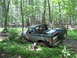 1991 Ford Bronco - Ford Bronco navigating a muddy trail surrounded by dense forest foliage.