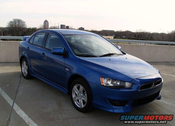 Blue 2009 Mitsubishi Lancer parked on a rooftop with buildings in the background