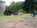 1988 Ford Bronco - People gather around two SUVs in an open field near trees and a large concrete structure.