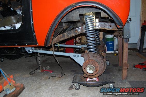 Orange vehicle's front suspension and brake assembly on a jack stand