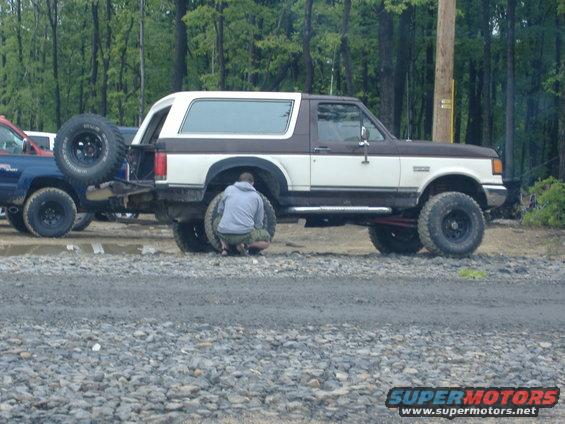 1988 Ford Bronco with spare tire on rear, two people working on rear tire