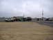 1988 Ford Bronco - Multiple off-road vehicles are parked in a gravel lot under an overcast sky.