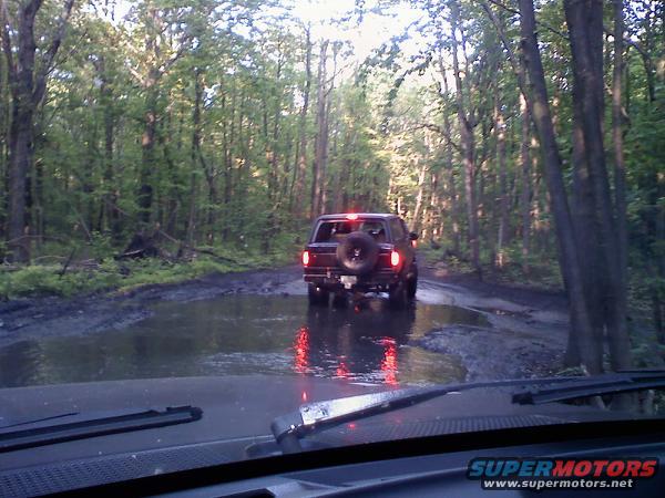 1988 Ford Bronco rear view driving through muddy forest road