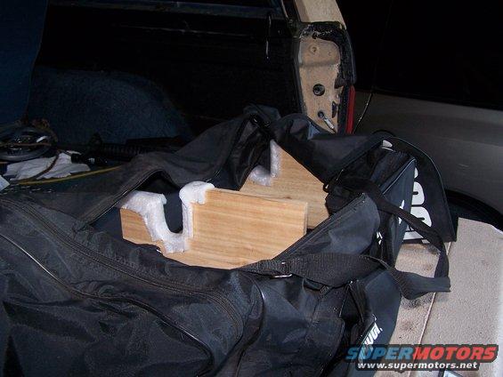 Black duffel bag with wooden supports inside an open vehicle cargo area