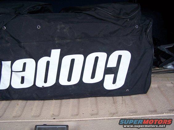 Black bag with white lettering that reads 'cooper'. Part of a Supermotors.net watermark is visible
