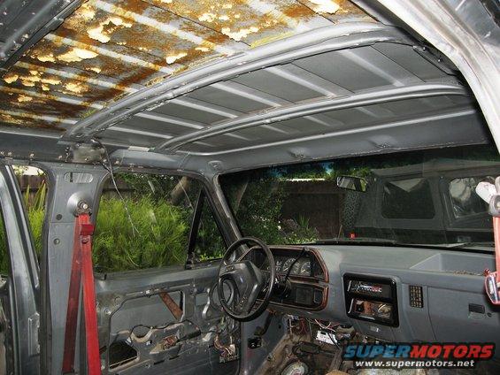 Interior view of vehicle with rusted roof lining and exposed door panels