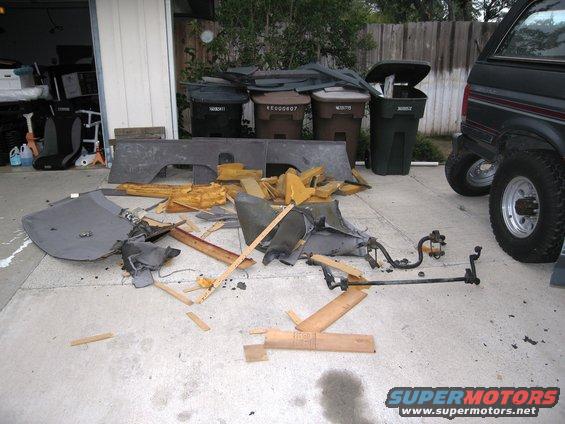 Disassembled interior parts on concrete next to a black SUV