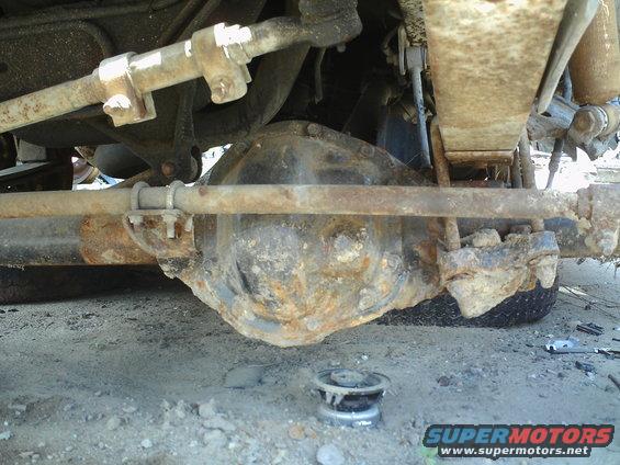 Undercarriage view of a rusty differential and suspension parts