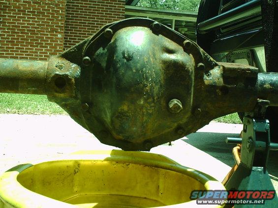 Rusty differential assembly on a jack stand over a yellow drain pan