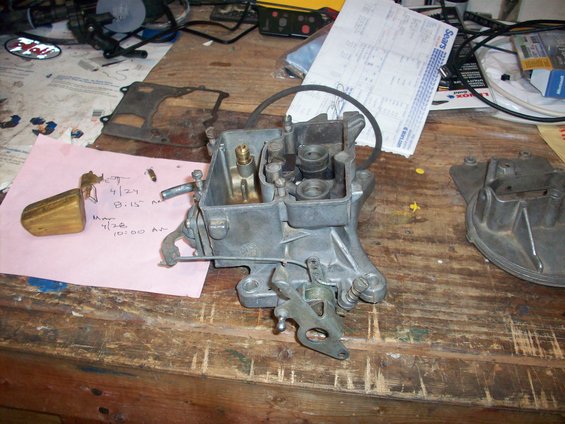 Carburetor on a wooden workbench with a pink note and Sears receipt