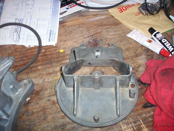 metal carburetor part on a wooden workbench with tools and papers