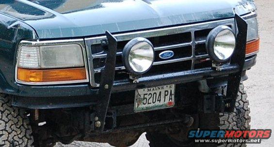 1993 Ford Bronco front grille with Ford logo, aftermarket bumper, and two large driving lights. Maine license plate 5204 PA is visible