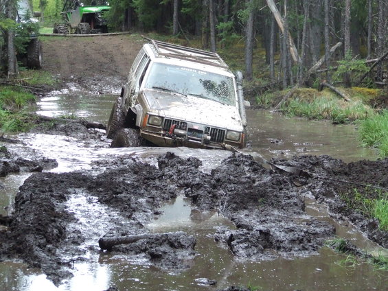White Jeep Cherokee stuck in mud, front winch visible