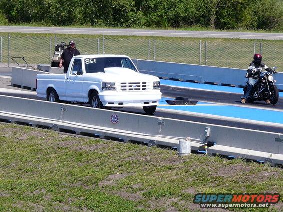 1994 Ford F-150 pickup truck with a hood scoop on a drag strip, motorcycle in background