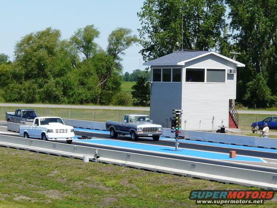 Silver 1980s Ford F-150 truck on a drag strip, front 3/4 view