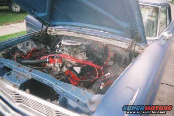 Blue 1964 Ford Galaxie engine bay with red spark plug wires and a V8 engine