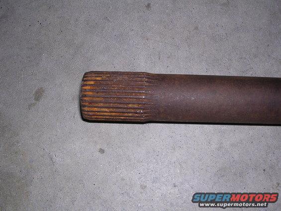 Rusted axle shaft with splines on a concrete surface