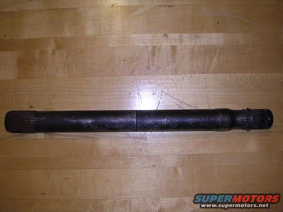 Driveshaft with splines on both ends, lying on a wooden surface