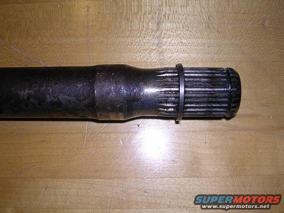 Driveshaft part with splines and a retaining ring on a wooden surface