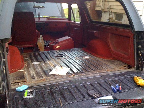 Interior of an SUV cargo area with red seats and floor. Tools are on the tailgate
