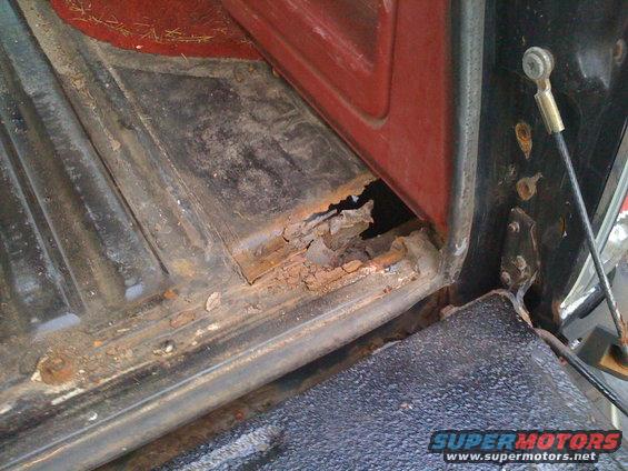Heavily rusted interior floor panel and door jamb of a vehicle