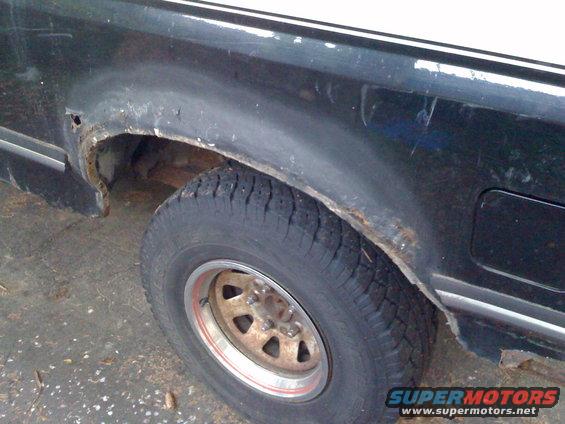 1988 Ford Bronco rear wheel well showing significant rust damage and a worn tire