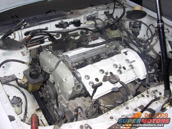 White engine bay with exposed engine components, hoses, and wiring