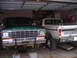 1979 Ford Bronco - Two Ford trucks are parked inside a garage, with the front truck on jack stands for maintenance.