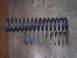 1979 Ford Bronco - Comparison of two coil springs, one new and one used, against a concrete floor.