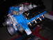 1979 Ford Bronco - A blue engine with black valve covers and chrome exhaust headers is displayed on a red engine stand.