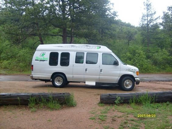 Side view of a white 2006 Ford E250 van with green 'Hays Trees' decals