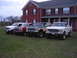 1979 Ford Bronco - A collection of Ford trucks and SUVs are lined up on a grassy lawn in front of a large brick house.