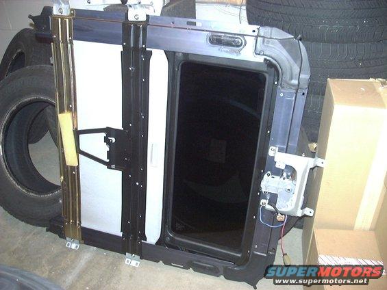car sunroof assembly with dark tinted glass and metal frame, next to tires and boxes