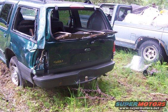 Green Ford Explorer with rear damage, broken windows, and a chain attached to the bumper