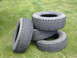 1988 Ford Bronco - Stack of four used tires sitting on the grass.