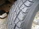 1988 Ford Bronco - A close-up view of a tire and part of the vehicle's suspension system.