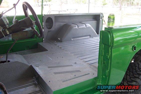 Green 1976 Ford Bronco interior and bed, showing bare metal floor and green painted body panels. A can of BL sits on the rear quarter panel
